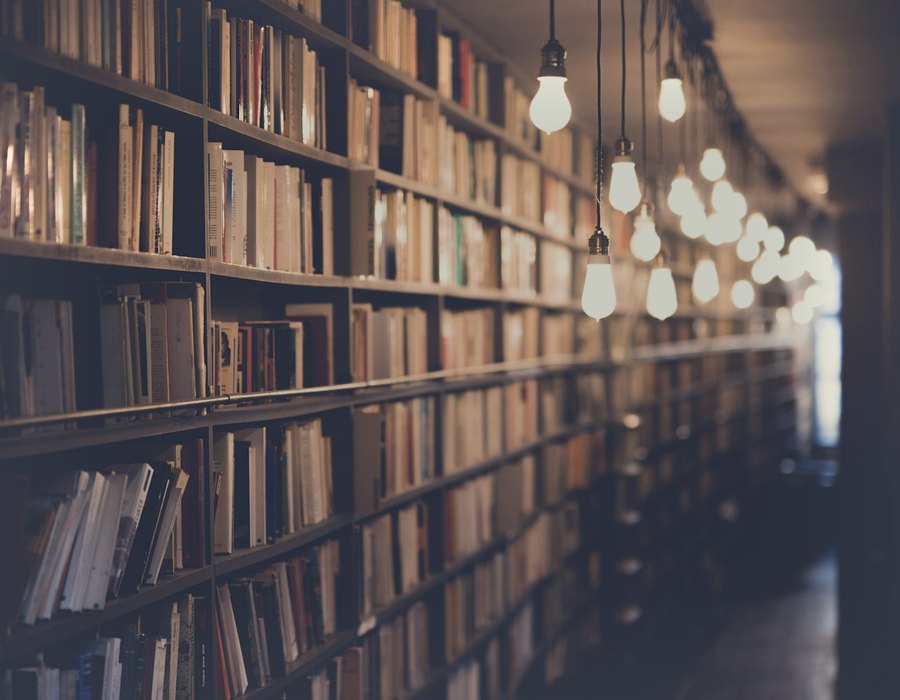 Aisle of packed library bookshelves under hanging lights